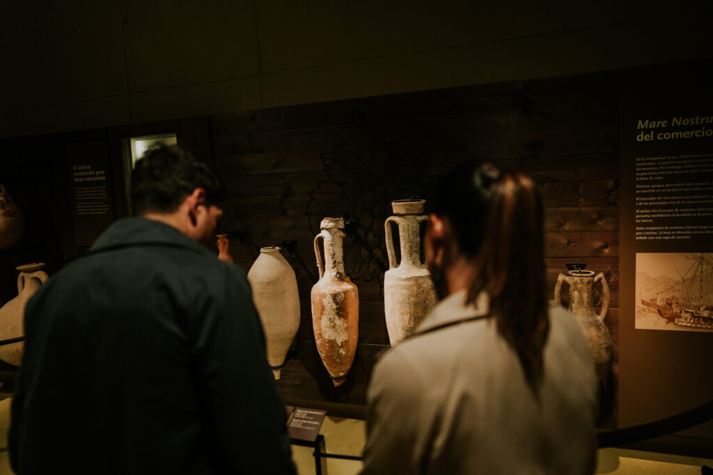 Visitantes observando ánforas y piezas antiguas en una sala del museo